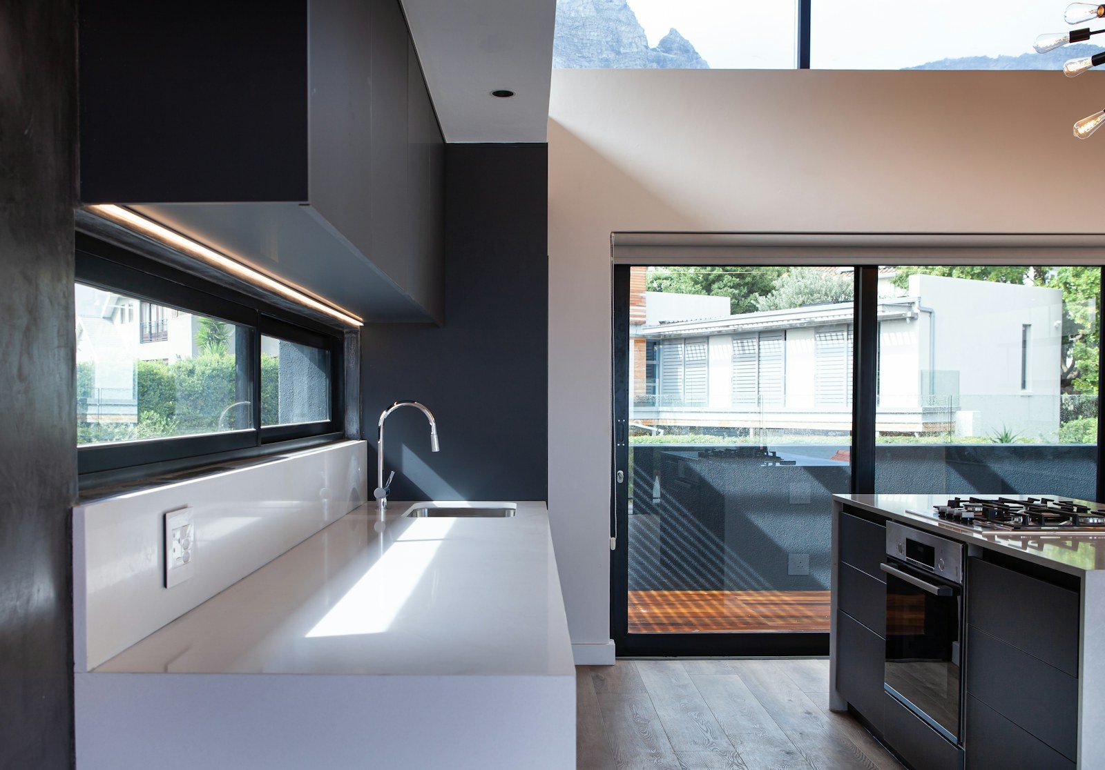 Puerta corredera acristalada de marco oscuro junto a una cocina como referencia para ventanas de aluminio